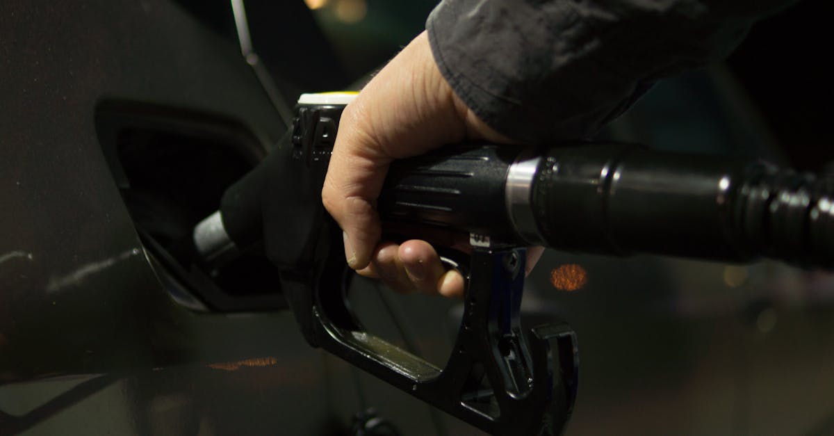 Close-up of a person refueling a car at a gas pump during night.