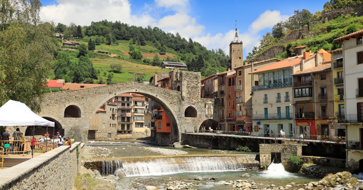 Picturesque view of the historic stone bridge and charming village of Camprodon, Spain on a sunny day.