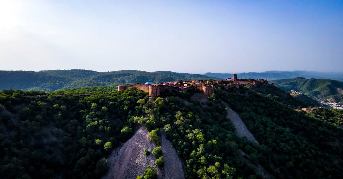 A stunning aerial view of Nahargarh Fort in Jaipur, set against the lush Aravalli hills under a clear blue sky.