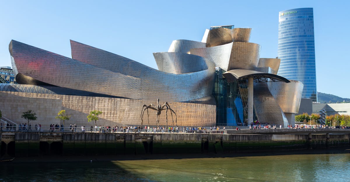 The iconic Guggenheim Museum in Bilbao by the river under a clear blue sky.