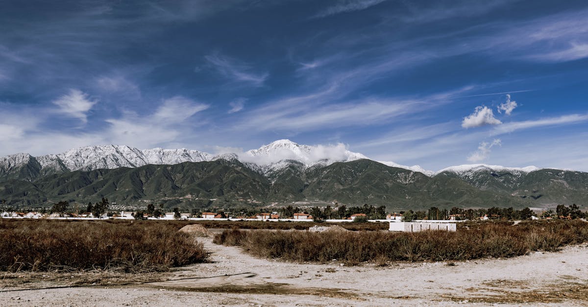 Scenic view of snow-capped mountains with a vibrant blue sky and village in the foreground.