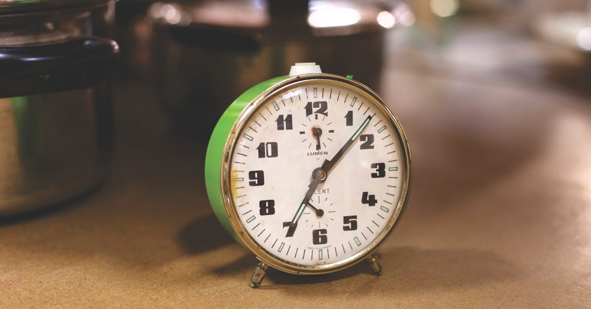 Close-up of a retro alarm clock next to kitchen pots, emphasizing time management in cooking.