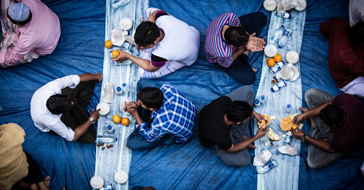Top view of a group enjoying Iftar meal on blue fabric during Ramadan fasting period.