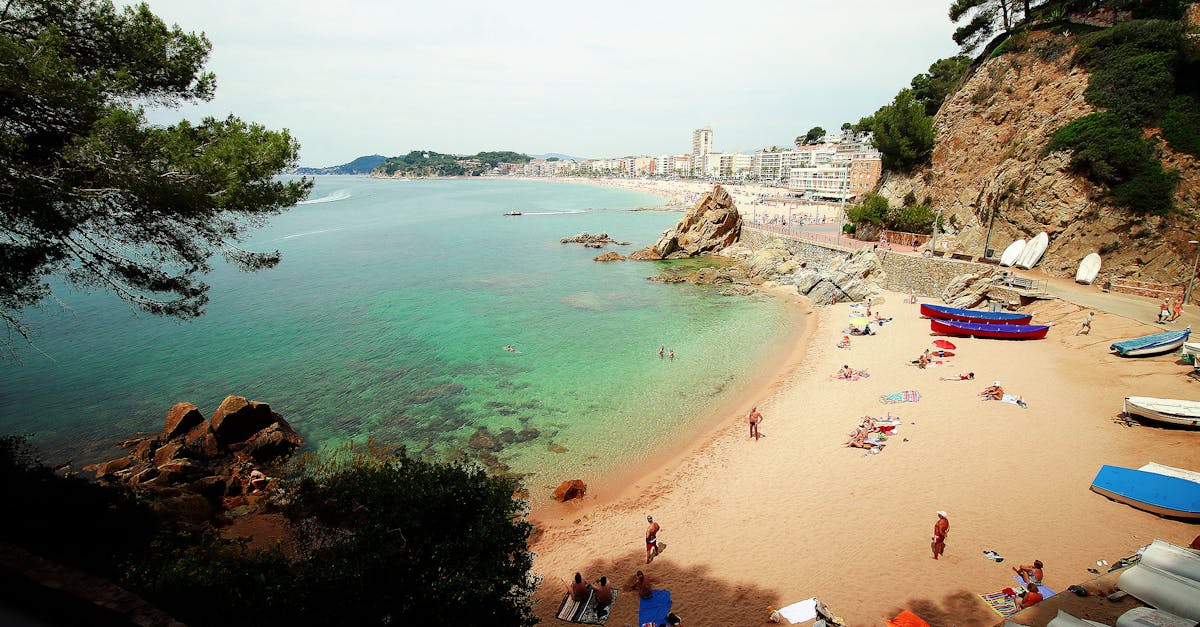 A picturesque Mediterranean beach scene with turquoise waters, sandy shore, and sunbathers enjoying a summer day.