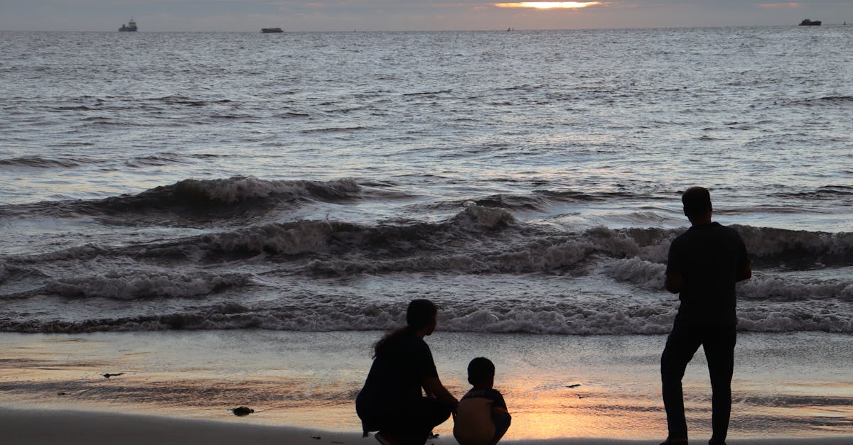 A family silhouetted against a stunning sunset at Kanyakumari Beach, India.