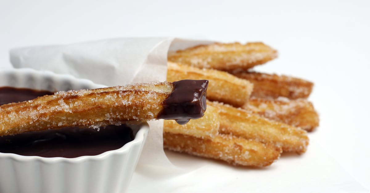 Delicious churros coated in sugar, dipped in rich chocolate sauce, perfect for dessert lovers.