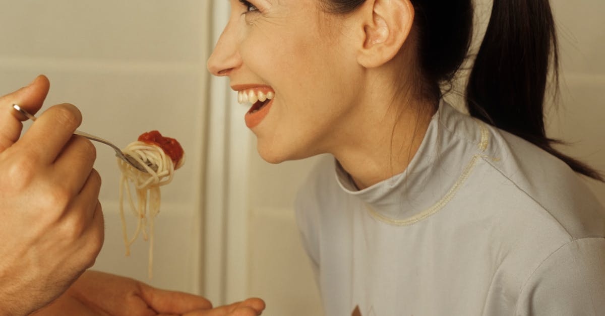 A joyful couple shares a romantic indoor meal, feeding each other spaghetti.
