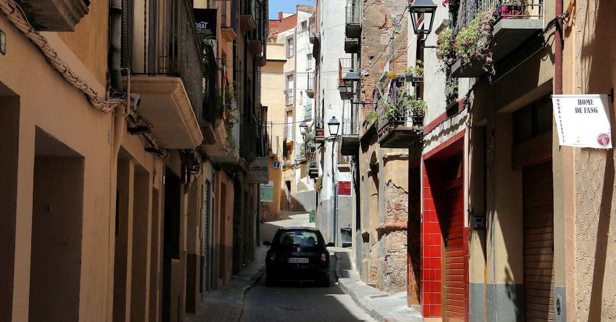 Explore a picturesque alley with rustic architecture and vibrant balconies in Falset, Spain.