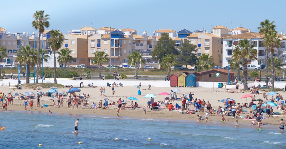 Enjoy a lively summer day at a bustling Mediterranean beach with people enjoying the sunshine.