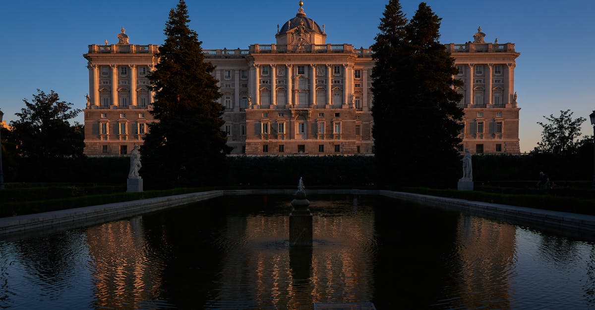 Majestic view of the Royal Palace of Madrid reflecting in the Sabatini Gardens pool during twilight.