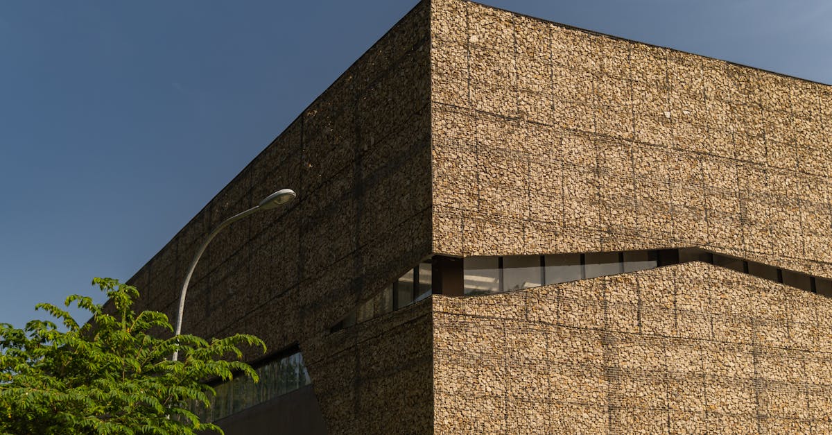 Corner view of a modern building with distinctive stone facade under a clear blue sky.