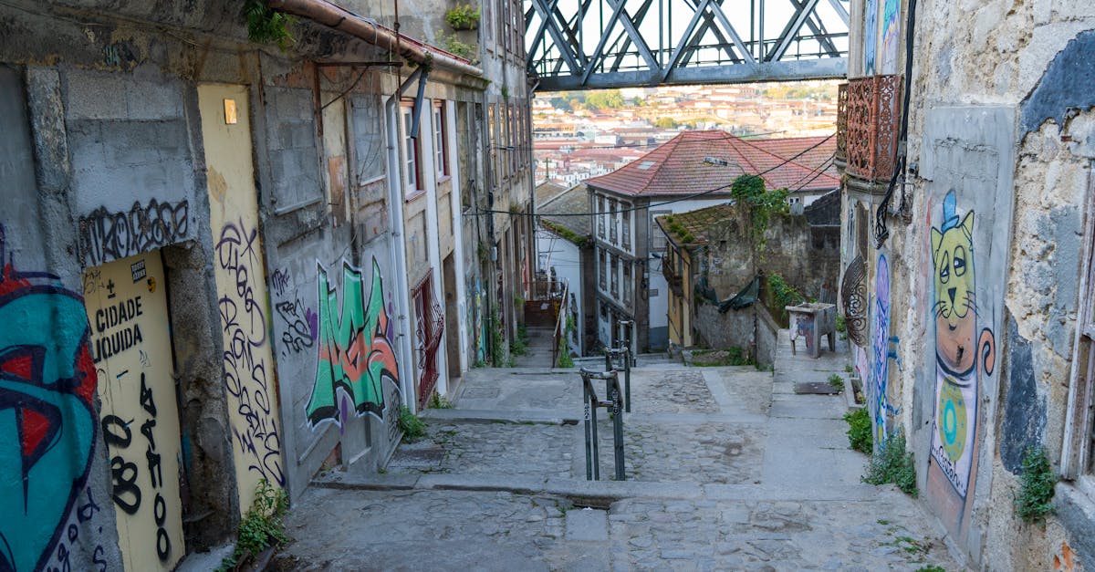 Vibrant urban alley in Porto decorated with colorful graffiti and street art under a bridge.