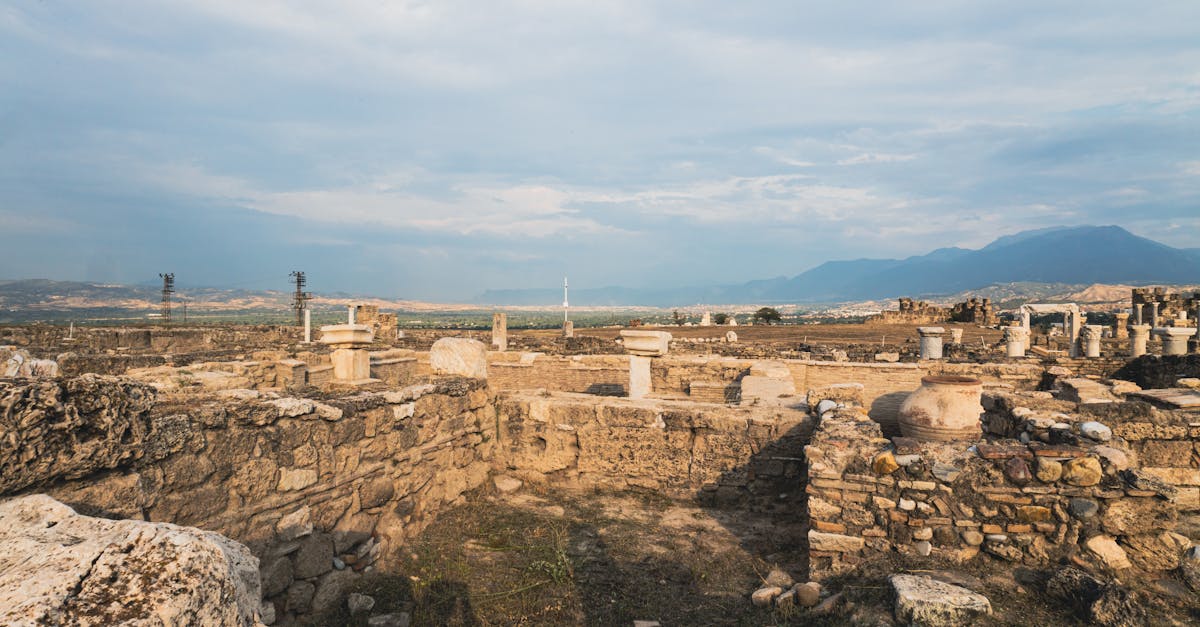 Explore the ancient ruins of Laodicea with a scenic backdrop of mountains under a blue sky.