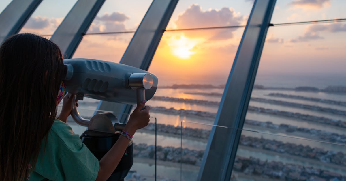 A young girl uses binoculars to view a stunning sunset over Palm Jumeirah in Dubai.