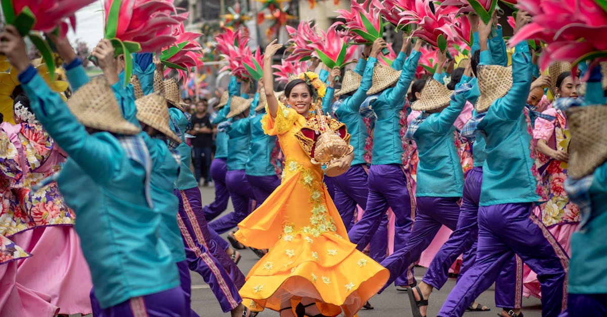 Colorful street festival with dancers in traditional clothing and large floral displays.