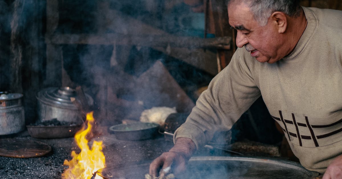 Senior man cooking with pots over an open flame in Denizli, Türkiye.