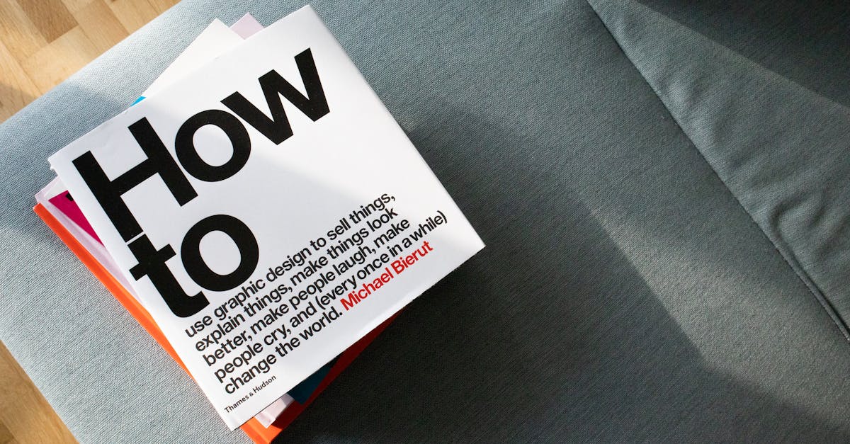 A collection of design books on a couch, showcasing 'How to' by Michael Bierut
