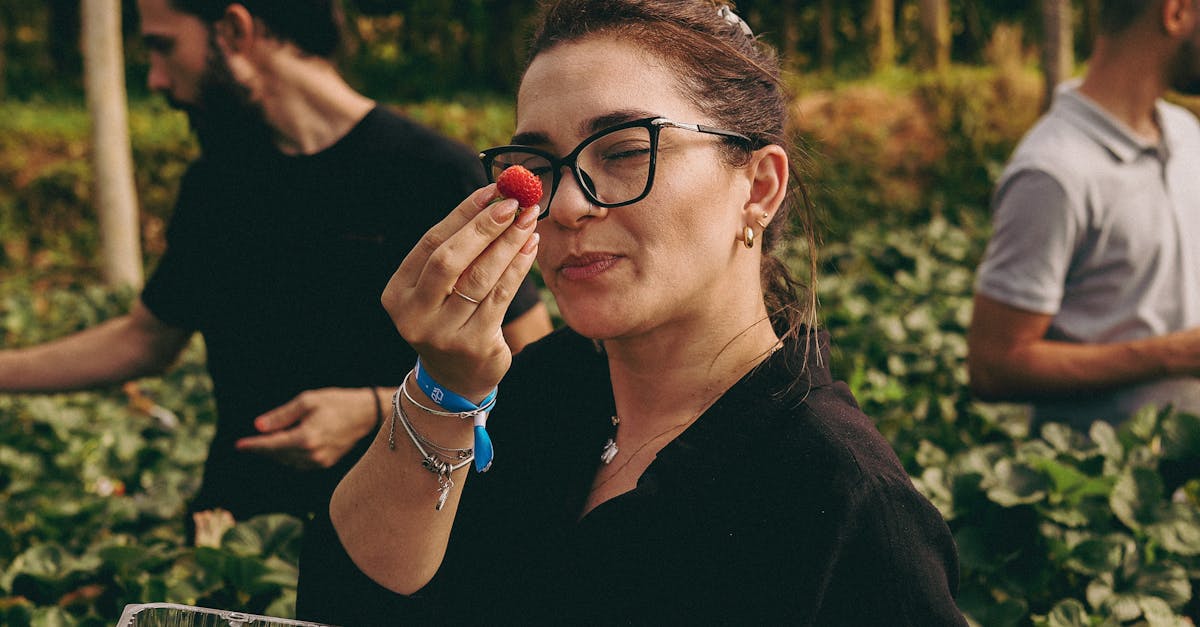Young woman savoring fresh strawberries in a sunny strawberry field, embracing harvest season.