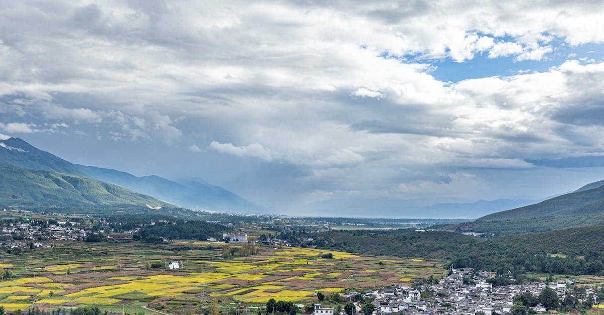 A breathtaking aerial shot of a picturesque valley with fields and mountains, under a dramatic cloudy sky.