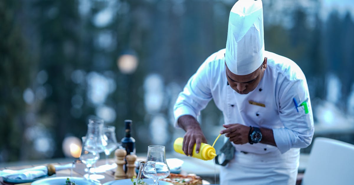 Chef expertly adds finishing touches to a gourmet dish at an outdoor restaurant setting.