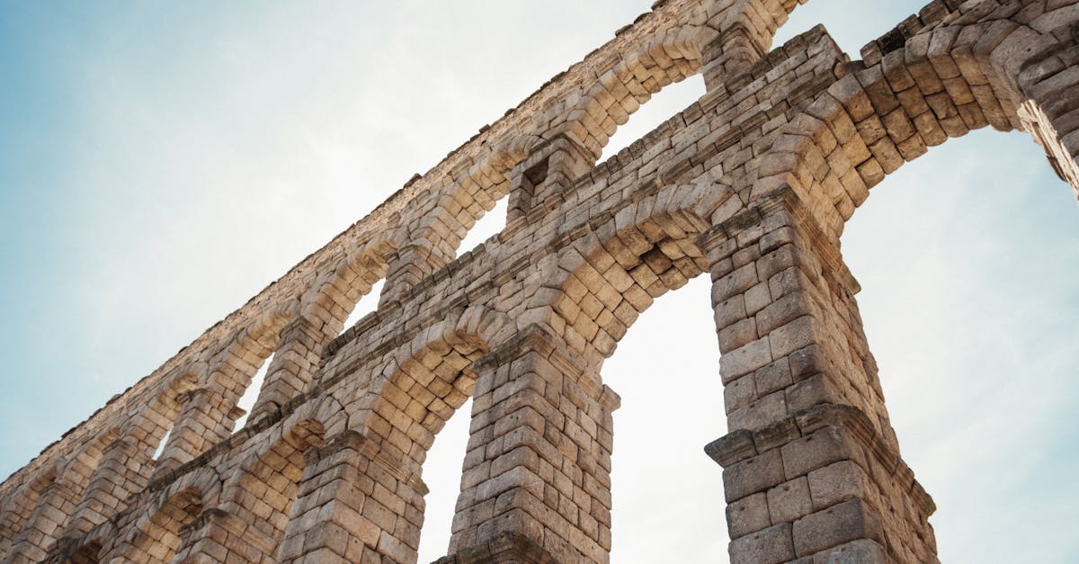 Low angle view of the historical Segovia Aqueduct's stone arches under a clear sky.
