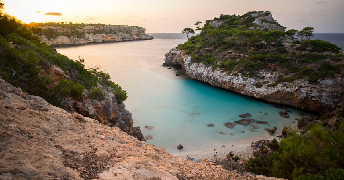 Idyllic cove at sunset with turquoise waters and rocky cliffs, perfect for a tropical escape.
