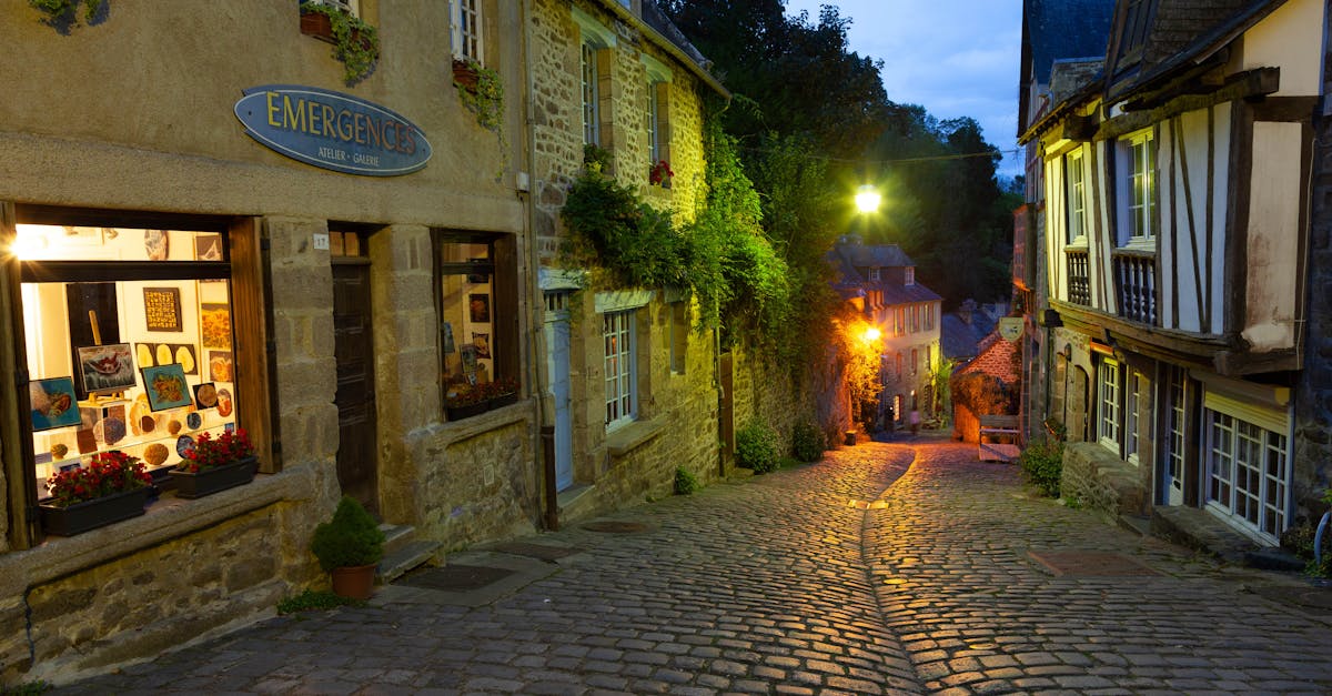 Charming cobblestone street in Dinan, Brittany, France, illuminated during dusk. A perfect blend of old-world architecture and evening glow.