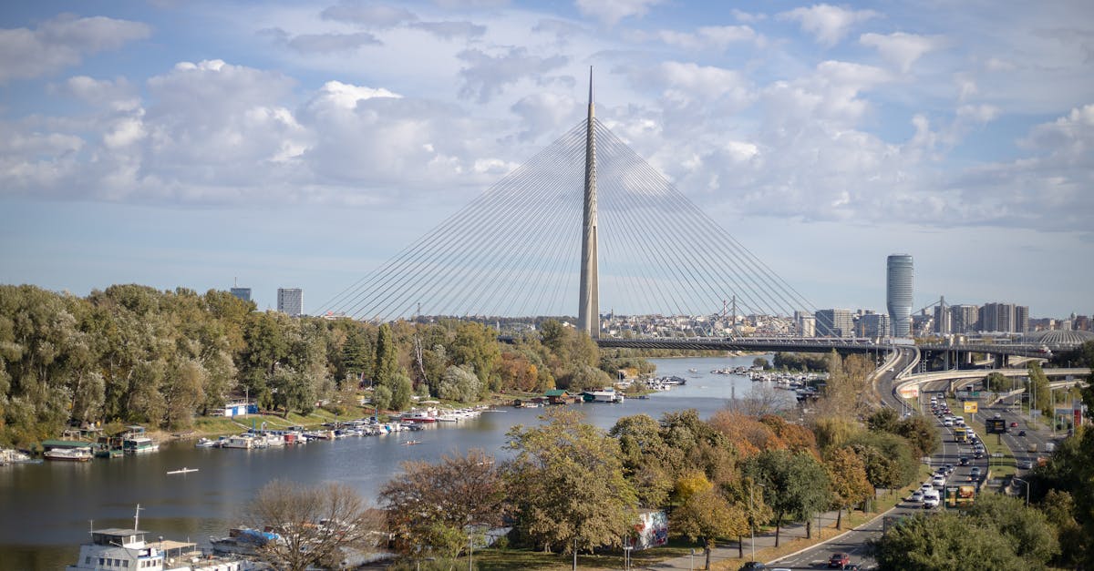 Stunning aerial photo of Ada Bridge spanning the Sava River in Belgrade, surrounded by urban and natural landscape.