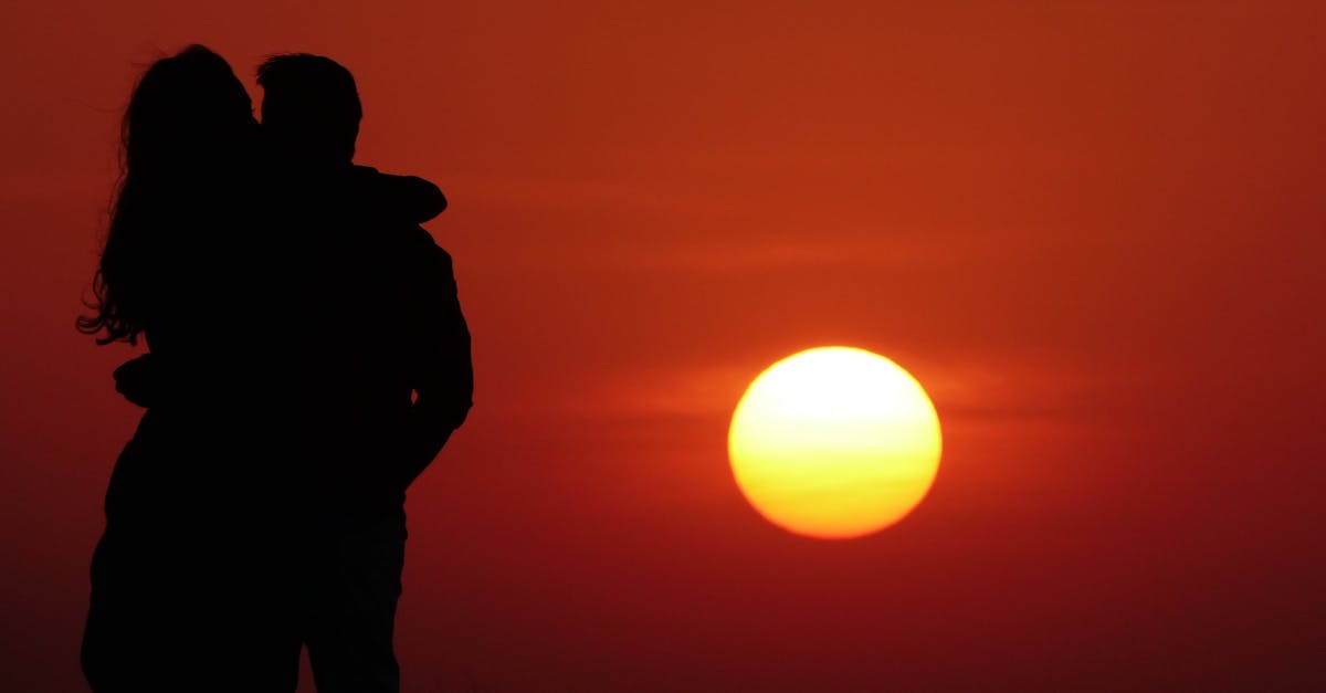 Silhouetted couple embracing during a stunning sunset, evoking romance.