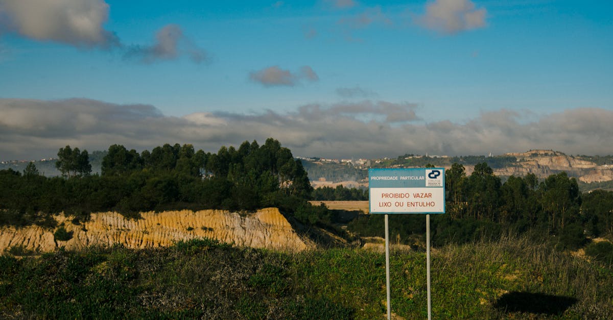 Wide view of a landscape with a clear blue sky, featuring a no dumping sign in a natural setting.