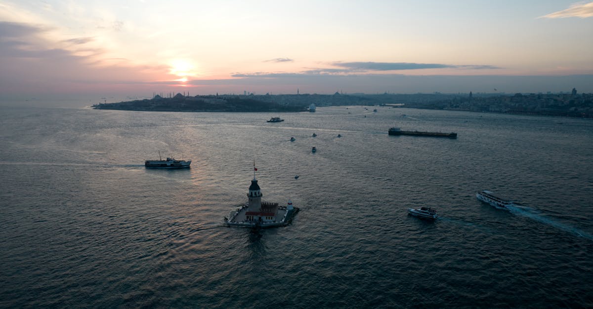 Stunning aerial view of Istanbul's Maiden's Tower at sunset with boats gliding on the Bosphorus.