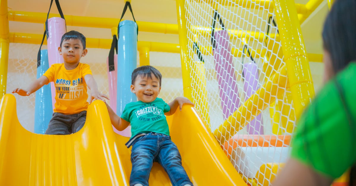 Two boys enjoying playful moments on a colorful indoor playground slide.