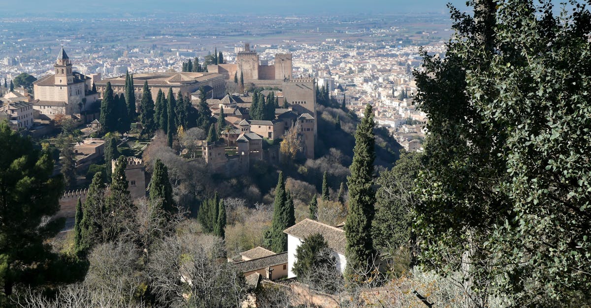 Stunning view of the Alhambra with Granada cityscape in Spain, surrounded by lush cypress trees.