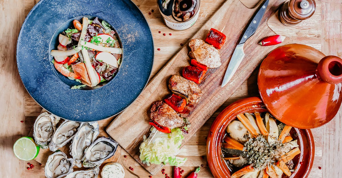 Top view of French gourmet dishes including seafood salad, grilled skewers, oysters, and wine in Angers, France.