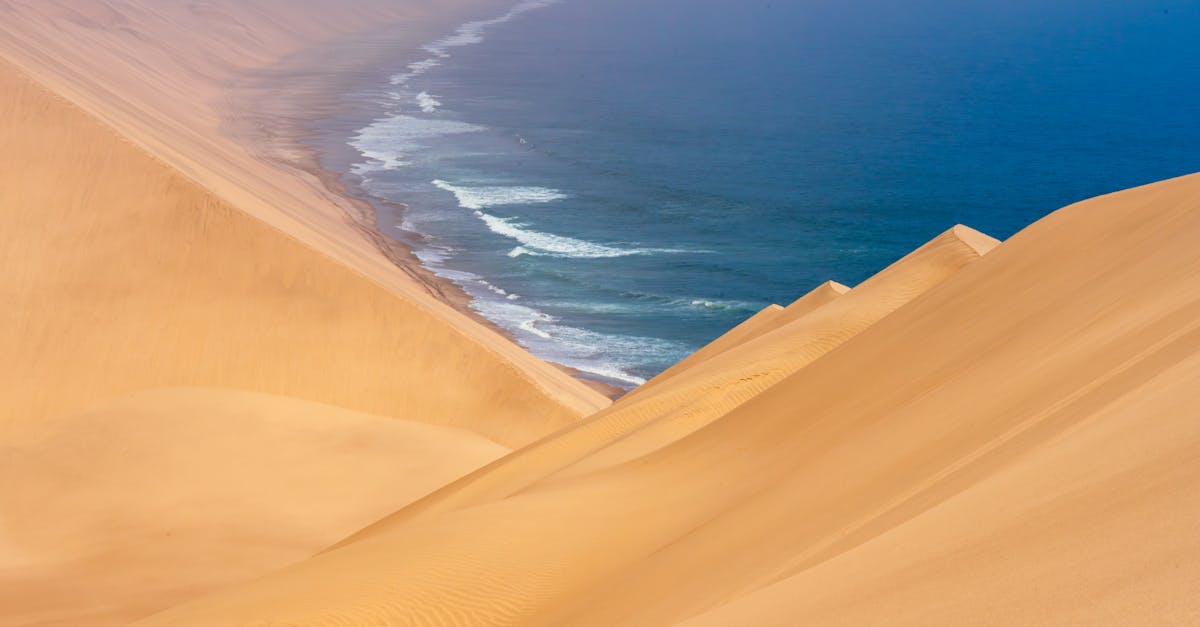 A breathtaking view of vast sand dunes merging with the ocean waves at a remote coastline.