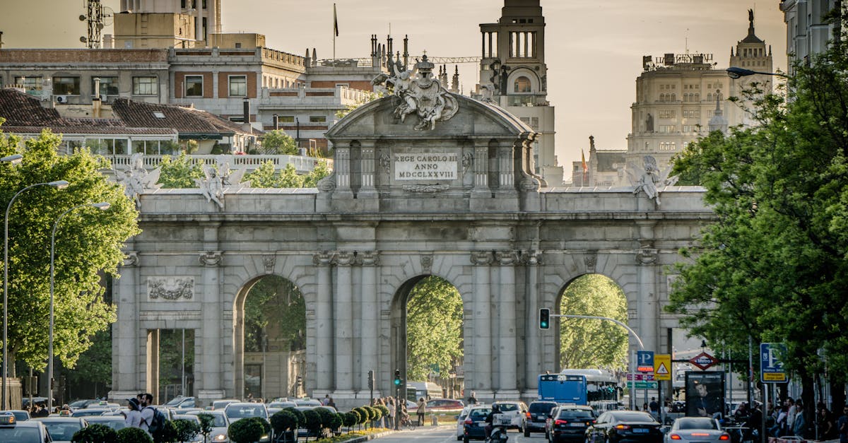 View of the historic Puerta de Alcalá in Madrid with traffic and city architecture.