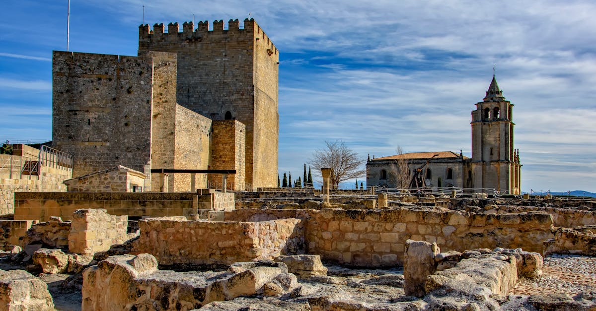 Explore the historic fortress and church under a clear blue sky in Alcalá la Real, Spain.