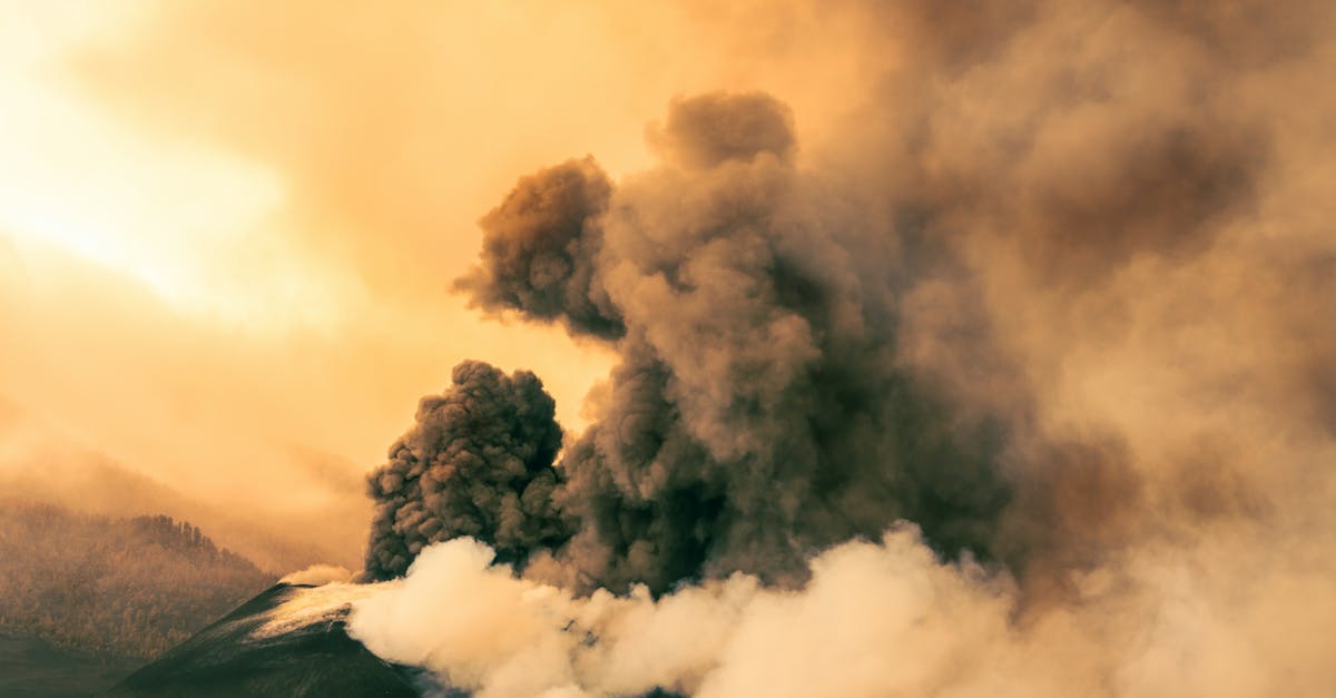 A stunning view of a volcanic eruption with billowing smoke at sunset, showcasing nature's power.