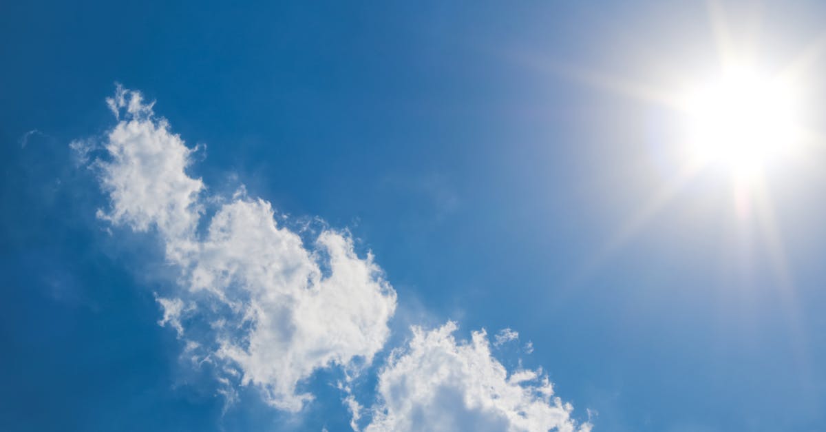 A clear blue sky with fluffy clouds and bright sunshine, representing a perfect summer day.