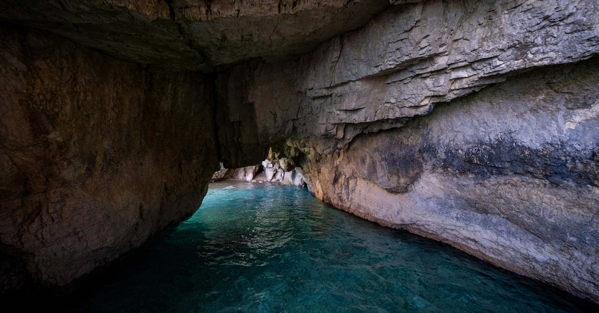 Explore a stunning coastal cave with tranquil blue waters and geological formations.