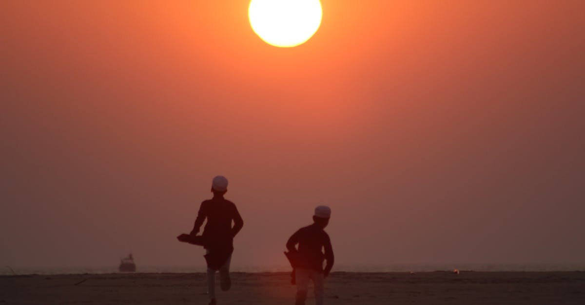 Silhouettes of children running on the beach against a vibrant sunset backdrop.