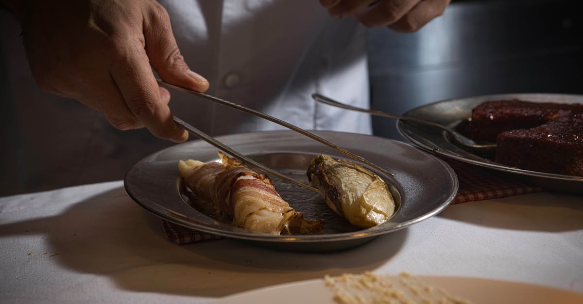 Chef arranging a gourmet dish with precision in a dimly lit kitchen.