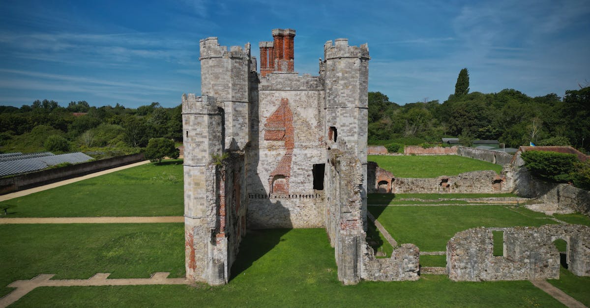Aerial view of Titchfield Abbey ruins with lush green surroundings in Titchfield, England, under a bright blue sky.
