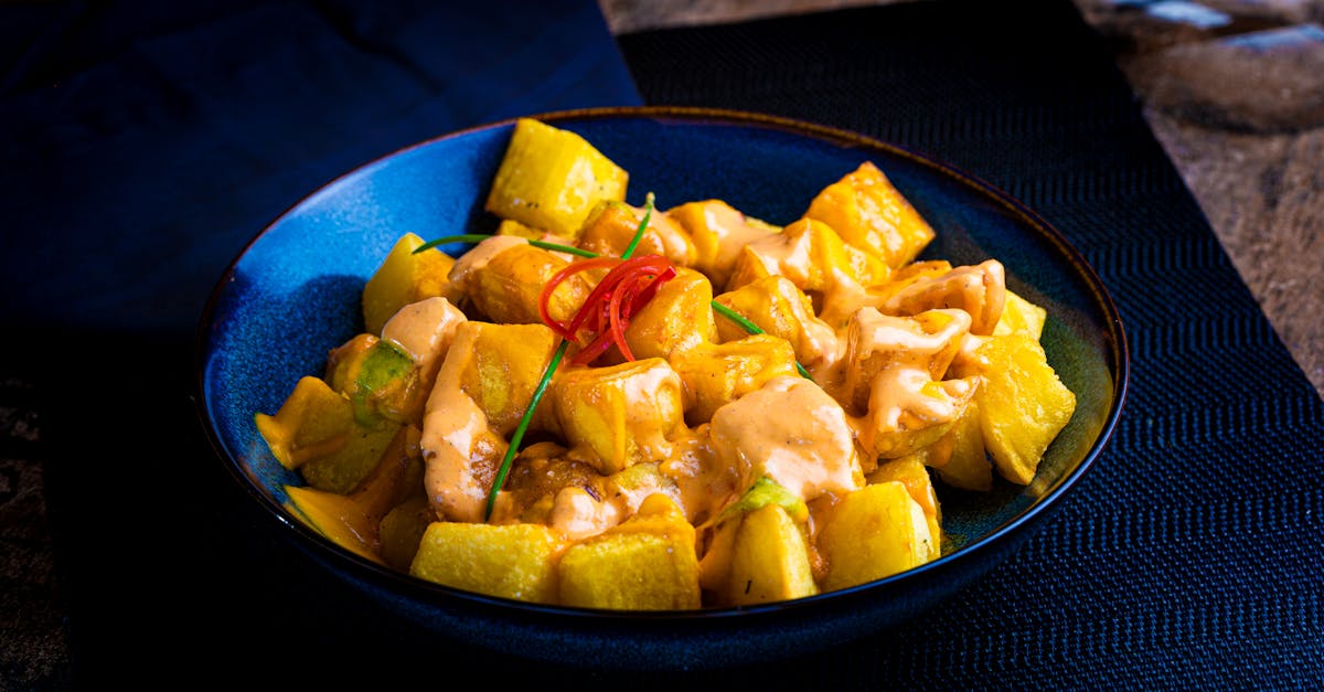 A vibrant dish of patatas bravas with rich sauce on a blue plate, perfect for culinary enthusiasts.