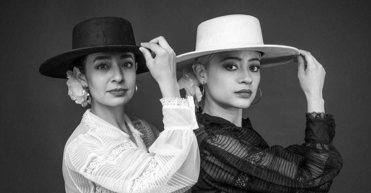 Black and white portrait of two female flamenco dancers in traditional hats, showcasing Spanish culture.