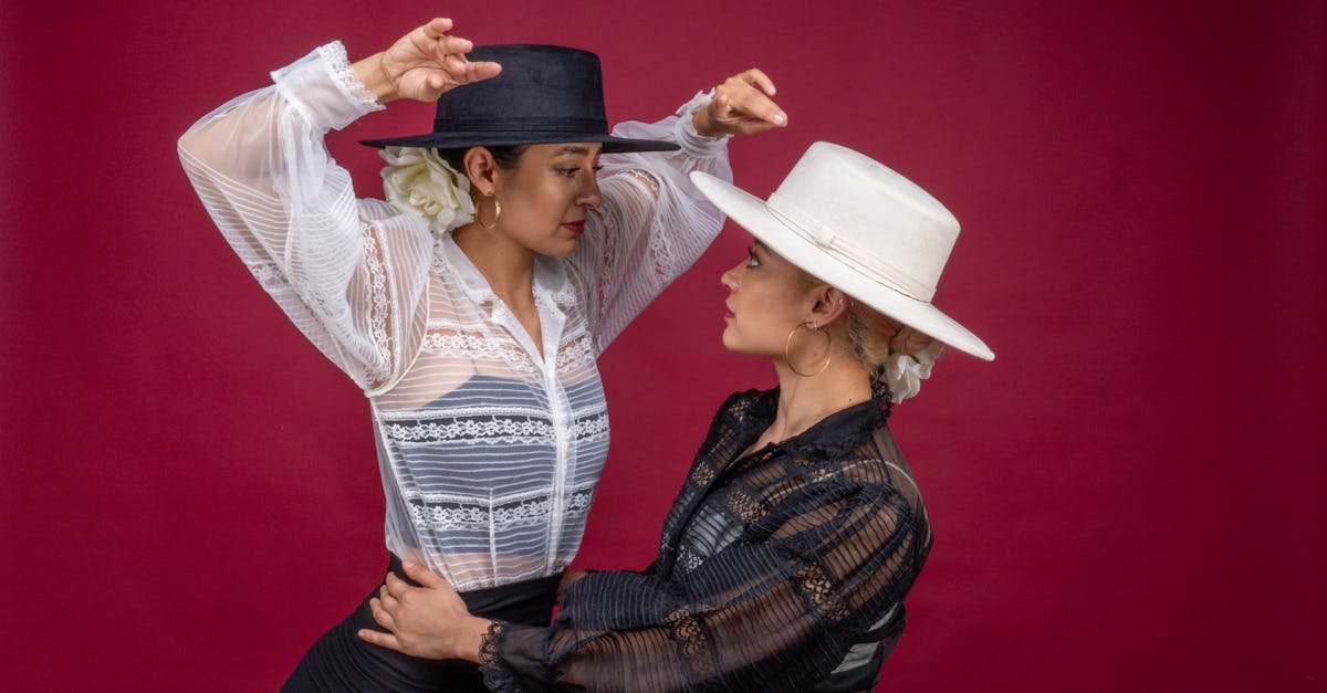 Two female flamenco dancers in traditional attire posing against a vivid red backdrop.