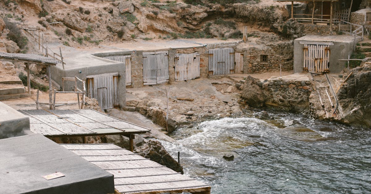 Old rustic fishermen's huts by the rocky coastline in Ibiza, Spain, showcasing Mediterranean charm.