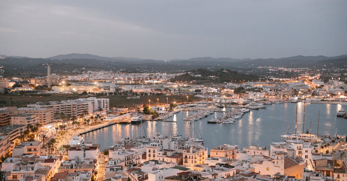 A scenic aerial view of Ibiza's marina at dusk, showcasing vibrant city lights and bustling harbor in Spain.