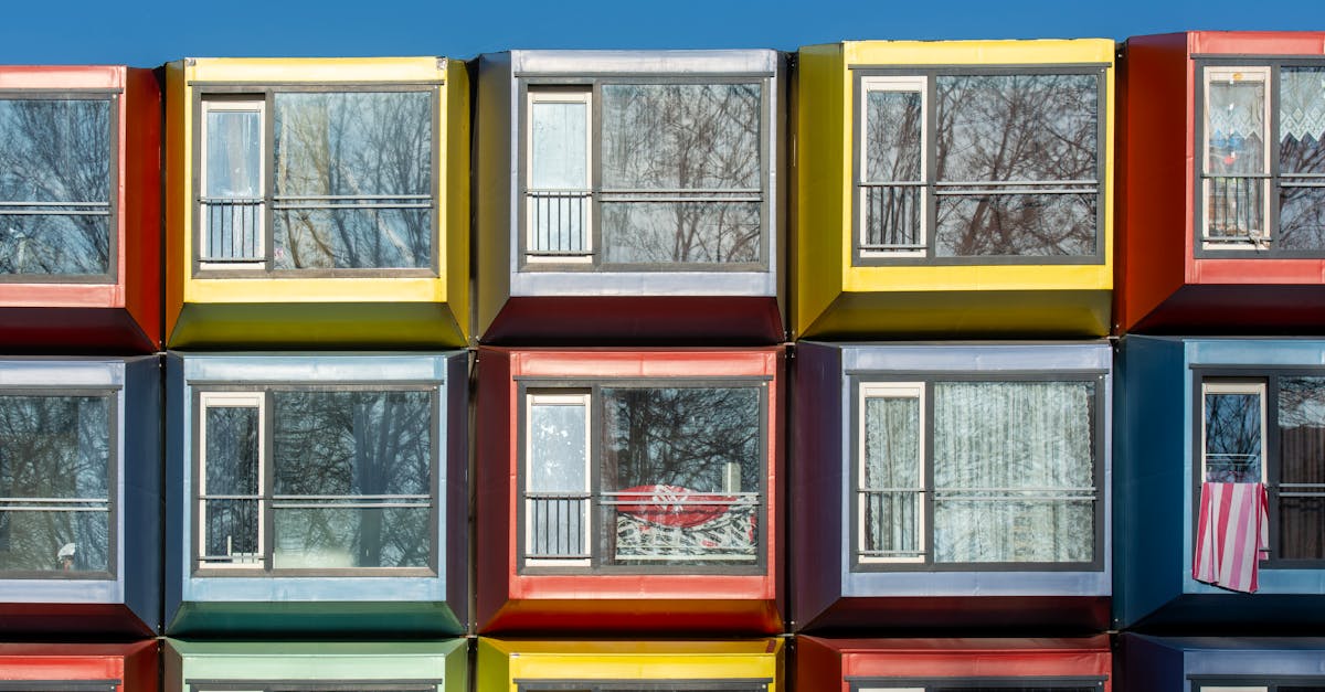 Close-up of vibrant modular apartment windows reflecting winter trees.