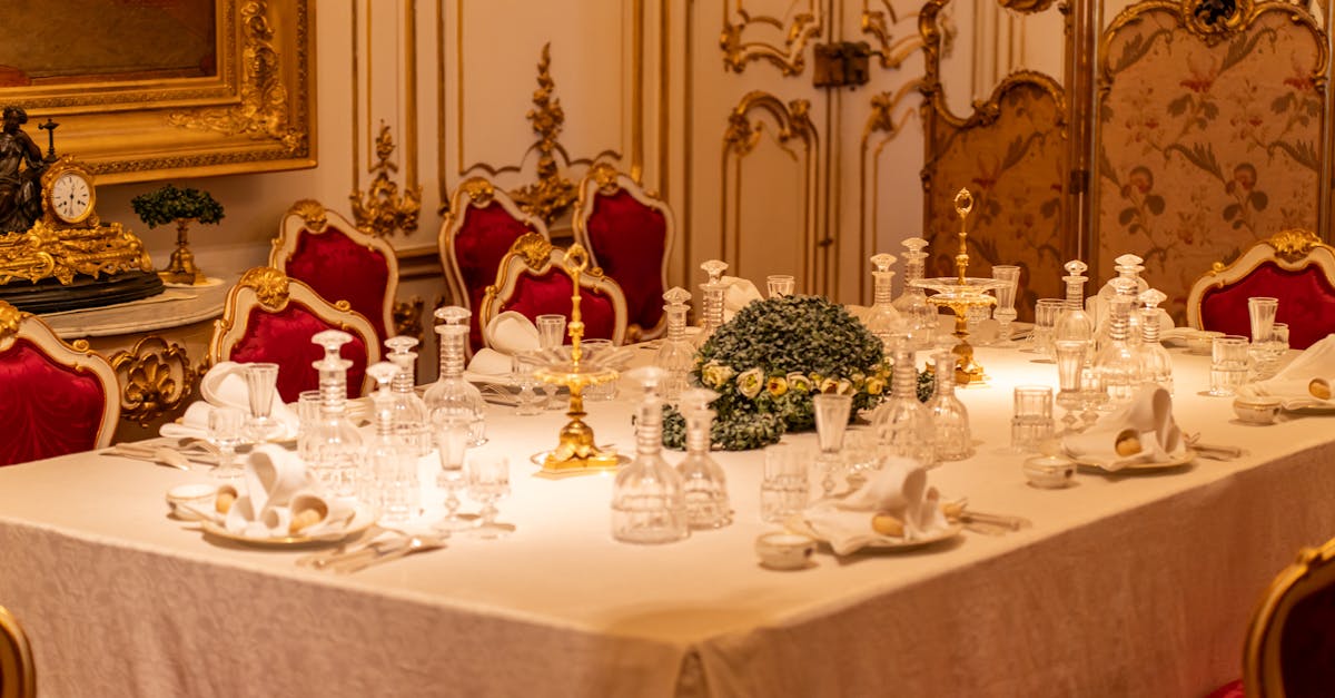 Elegant dining table set in a lavish, gilded room with crystal glassware and gold decor.